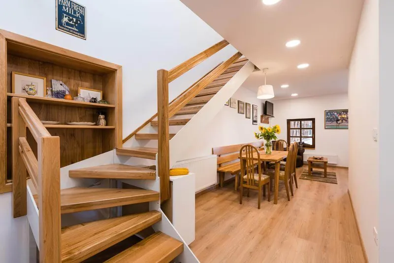 Interior of the Zynga apartment with wooden stairs and a dining area.