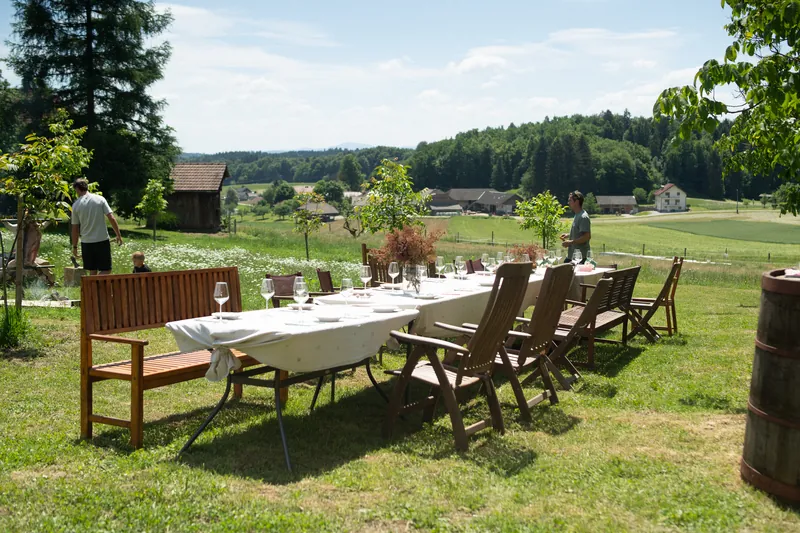 A long laid table on the meadow with a view over the surrounding hills.